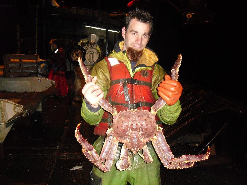 Person holding a large crab in a dark setting
