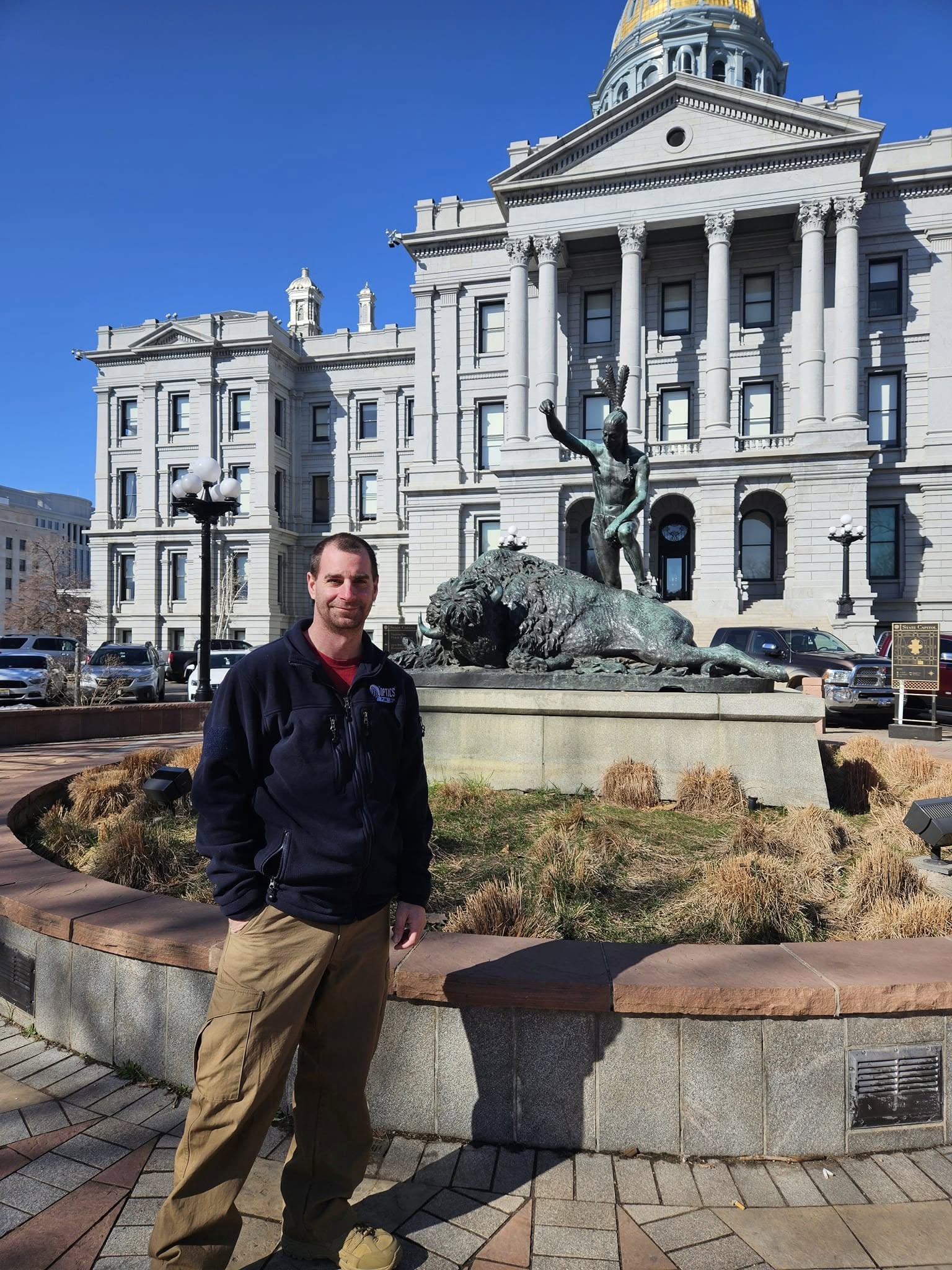 Justin standing in front of a large government building with a statue and fountain.